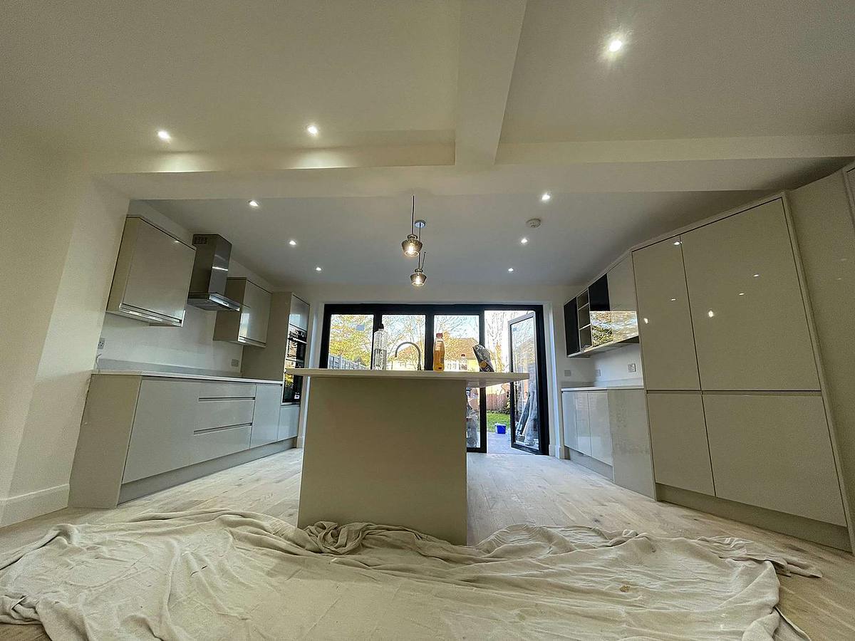 An open-plan kitchen after a wall was removed, with a large island and bi-fold doors